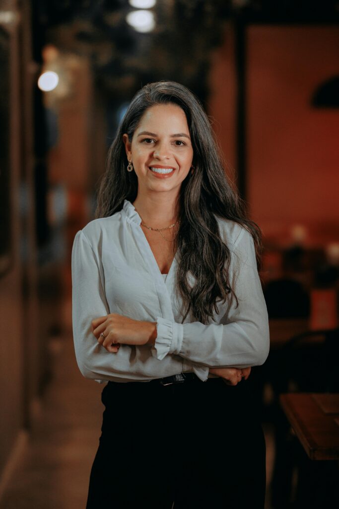 Confident businesswoman with long hair smiling in an indoor office setting.